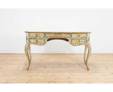 A painted pine writing table,early 20th century, Italian, with all-over scrolling foliate and gilt detail, the shaped top abo