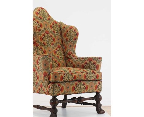 A William and Mary-style walnut wingback armchair, c.1900, with bulbous supports united by turned stretchers, terminating in 