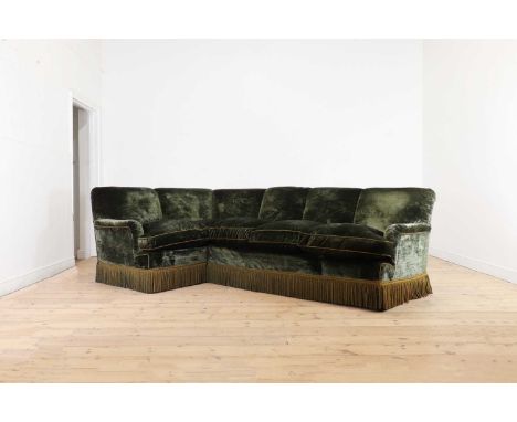 A green velvet upholstered corner sofa, second half of the 20th century, possibly by Lenygon &amp; Morant, with bullion fring