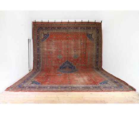 A large country house wool carpet, early 20th century, Anatolian, the red field centred with a shaped medallion, with all-ove
