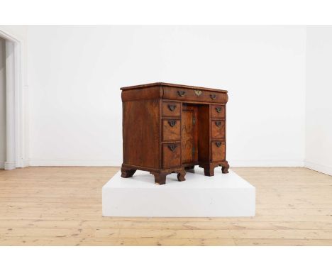 A George I walnut and feather-banded kneehole desk, first quarter of the 18th century, the quarter-veneered top above an arra