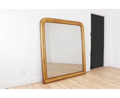A large giltwood overmantel mirror, late 19th century, with an arched top and incised foliate detail, with beaded moulding su