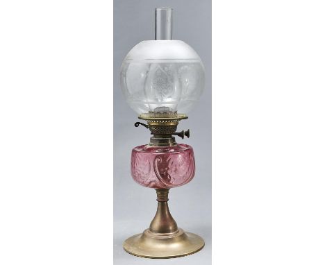 An Edwardian brass oil lamp, with moulded cranberry glass fount and brass burner, etched glass globe, 49cm h excluding chimne
