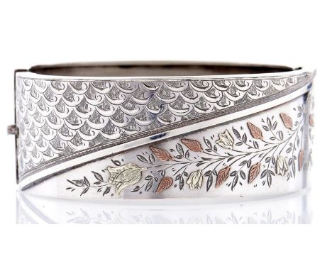 An aesthetic silver bangle, c1880, with coloured gold applied decoration, unmarked  