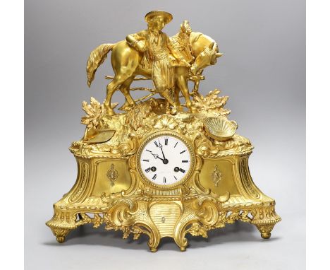 A 19th century French gilt brass mantel clock with man and horse, with key and pendulum, 38cm tall