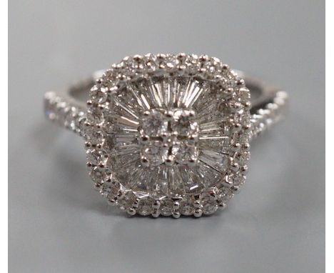 A modern 750 white metal, trapeze and round cut diamond set cushion shaped cluster dress ring, with diamond set shoulders, si