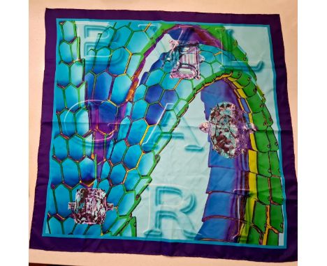 Bulgari/Bvlgari- A silk scarf in tones of turquoise, purple, green and gold having the brand name in large letters to the cen