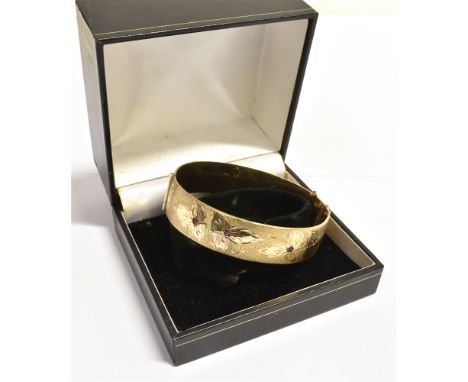 ROLLED GOLD ENGRAVED CUFF BANGLE 15.9mm wide with bright cut floral engraving to front set with red synthetic sapphires, hing