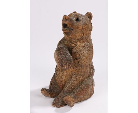 Early 20th Century Black Forest bear, seated with a paw raised, set with glass eyes, 18cm high