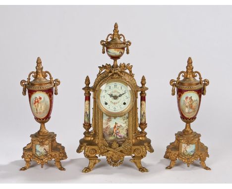 Gilt metal clock garniture, the urn finial above a leaf mounted arched case and paw feet, circular dial with a battery moveme