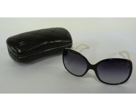 A pair of Chanel sunglasses,black tinted lenses with black and white frames, with enamel and silvered emblem to arms, in case