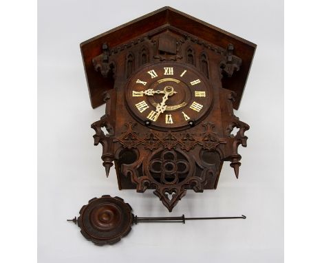 A 19th Century Black Forest cuckoo clock, the case pierced and fret cut in "Gothic" style, the circular face with applied ivo