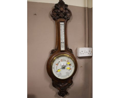 AN EDWARDIAN OAK CARVED ANEROID BAROMETER