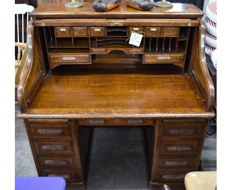 A large late 19th century roll-top oak desk with sliding tambour panel enclosing fitted interior over slides and drawers, 130