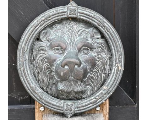 A cast aged metal ring door knocker on lion head mount, 22 cm wide