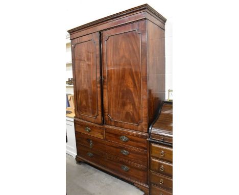 A 19th century mahogany linen press with panelled doors enclosing four slides over two short and two long drawers on ogee bra
