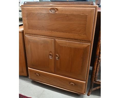 An Ercol (model 469) Windsor elm serving cabinet with moulded and recessed handles on fall front panel over two cupboards and