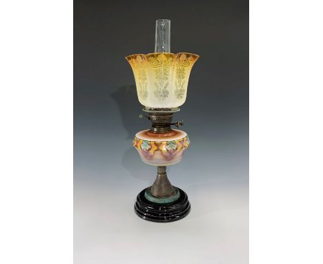 An early 20th century oil lamp on circular ceramic base, with patterned reservoir and etched graduated yellow to clear glass 