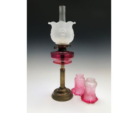 A Victorian brass oil lamp with cranberry glass reservoir ,overall height 67.5cm, together with two small cranberry glass sha