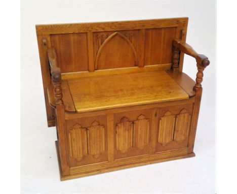 An oak monks bench, with hinged seat and triple carved linen fold base, width 94cm.