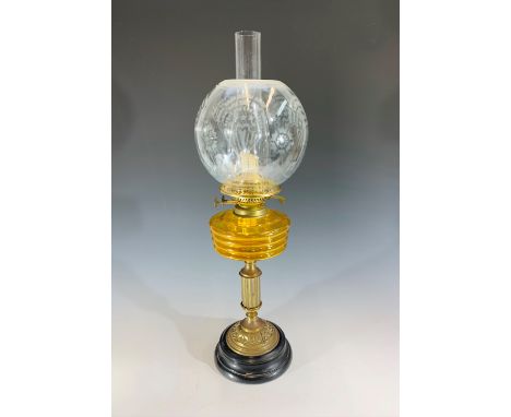 A brass oil lamp, with amber glass reservoir and etched glass globe. Height 63cm.