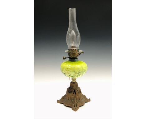 An early 20th century oil lamp, the green glass reservoir with gilded decoration. Height 34cm (excluding height of chimney).