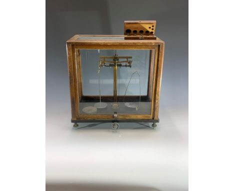 A set of laboratory scales, contained in a glazed case, height 43cm, with part set of cased weights.