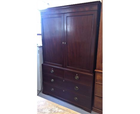 A George III mahogany linen press, with a pair of panelled doors, the lower part with two short and two long drawers, on brac
