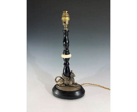 An early 20th century ebonised wood and ivory table lamp, the plated base in the form of a recumbent griffin. Height 39cm.