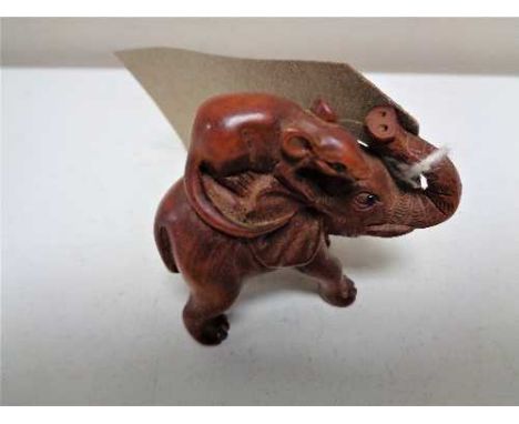 A carved fruitwood netsuke in the form of a rat riding an elephant