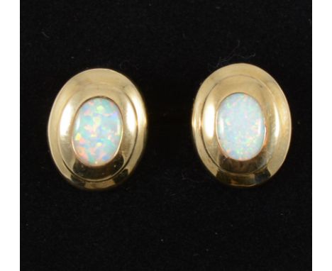 A pair of opal earrings, the oval cabochon cut stones set in yellow metal mounts with polished framework, pierced fittings wi