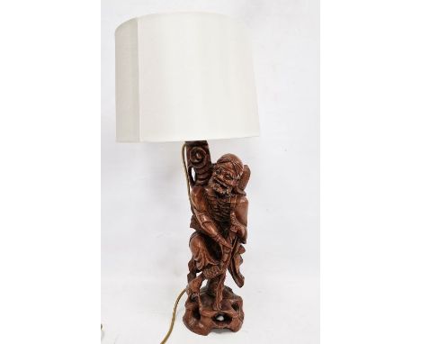 Chinese carved hardwood figural lamp base, 20th century, formed as a man holding on staff, on pierced rockwork, with scroll a