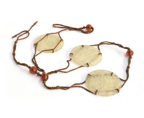 A Chinese belt comprising three pierced jade medallions strung on brown cord, each depicting two figures within flora, 5.8cm 