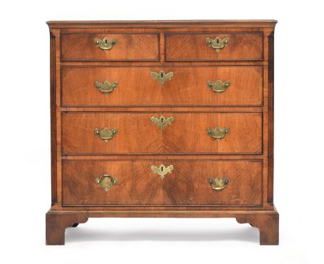 A George III walnut chest of drawers, the three quarter veneer top over two short and three graduating drawers flanked by ree