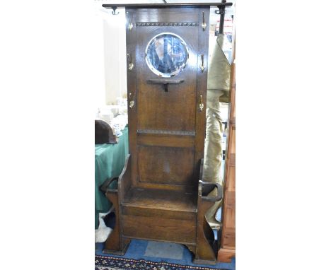 An Edwardian Oak Hall Stand with Circular Mirror Above Small Shelf, 6 Brass Coat Hangers, Central Hinged Seat to Store Flanke