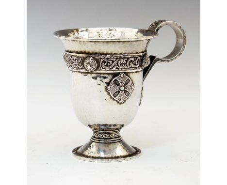 George V Celtic style hammered silver cup of bell shaped form having a loop handle with knotted decoration, the body with a c