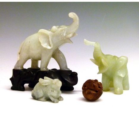 Two green hardstone figures of elephants, 7.5cm and 8.5cm high, a similar figure of a hare ,2.75cm high and a carved nut nets