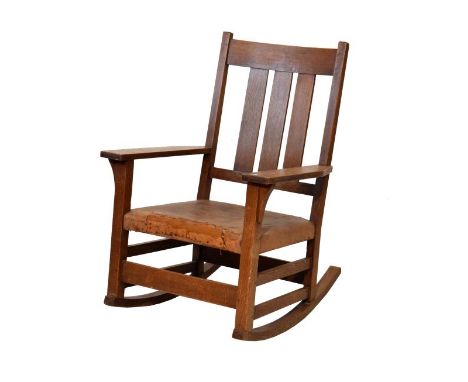 Gustav Stickley oak ladder back rocking chair having a triple lath back, wide flat arms, stuffed seat and standing on square 