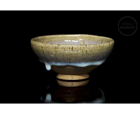 A small, modelled ceramic bowl. It has a small flared foot, followed by a deep circular body with a rounded profile. It is ad