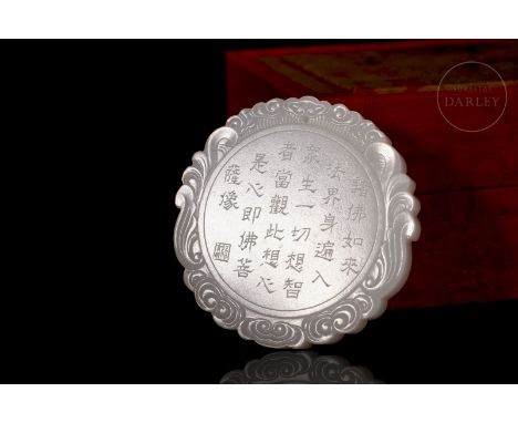 An elegant jade carving of pristine white. It is circular, with a thick wavy rim, decorated on both sides with a long poem an