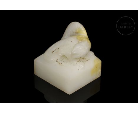 White jade with subtle amber-toned flecks carved in the form of a seal. It has a flat, quadrangular base, on which is placed 