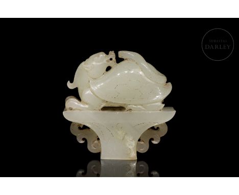 Carved white jade, with subtle ochre flecks. It has a trapezoidal base, decorated with engraved scrolls and scrolls in relief