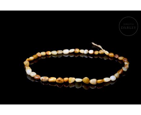 Elegant necklace made up of 43 small irregularly carved jade beads with rounded edges. The variation of white, ochre, amber a