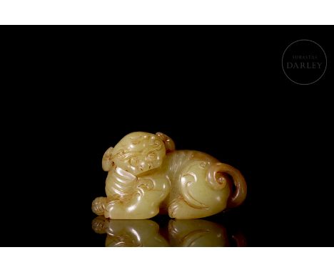 Carved jade of faint yellow, translucent, with broad reddish and amber tones. It shows a seated beast, with its torso resting