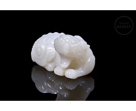 White jade carved in the form of a sturdy, recumbent mythical beast, with its body on bent legs and its head erect, showing a