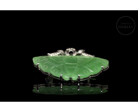 Brooch in 18k white gold and diamonds. Adorned with a piece of carved jade in the shape of a butterfly of an intense greenish