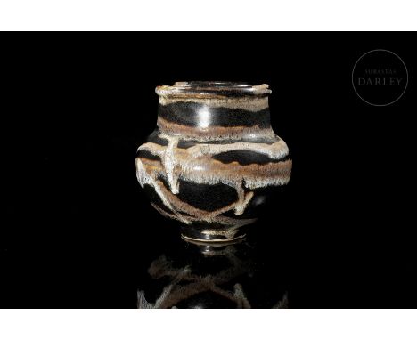 Ceramic modelled in the form of a vase, with a narrow circular foot, and a rounded body that is wider at the shoulders, with 