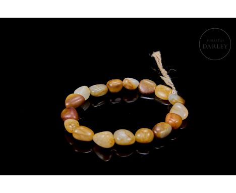 Small jade beads of whitish and ochre tones, with reddish stains. They are carved in an irregular shape, with rounded edges, 