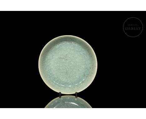 An elegantly modelled ceramic dish with a flat circular base surrounded by a thin rim. It is covered with a beautiful translu