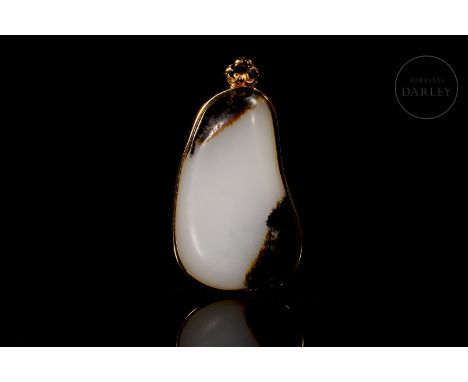 White jade, with reddish and brownish flecks. It has an oval shape, framed by a golden metal mount added later. The thin fram